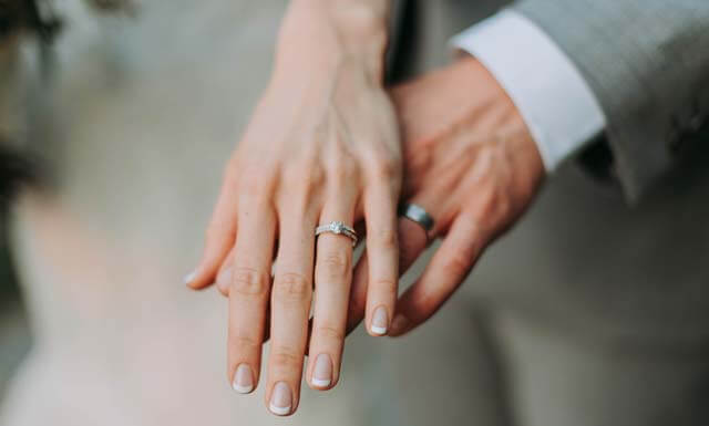 結婚指輪をはめて、2人手を乗せあった夫婦の画像